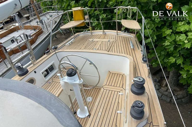 Een bovenaanzicht van een boot met een houten dek, een stuurwiel en twee zwarte lieren. — Tradewind 35