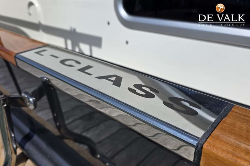 Een close-up van een houten handreling met een metalen plaatje waarop "L-CLASS" staat.