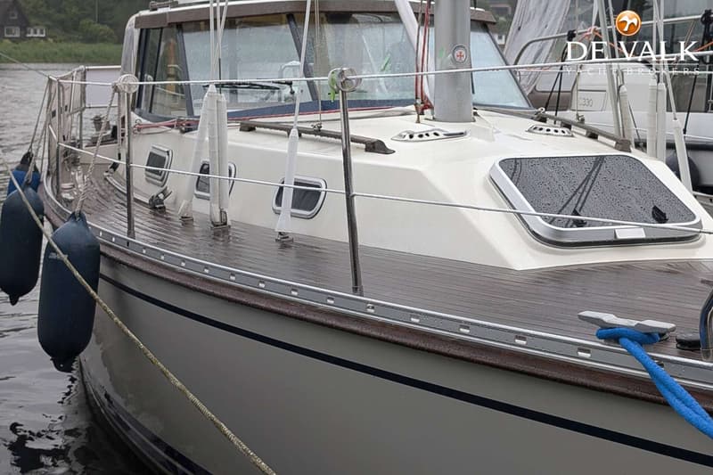 Een witte boot met een houten dek en een kajuit, liggend aan een kade met stootwillen en een blauwe lijn. — LM 35 Vitesse