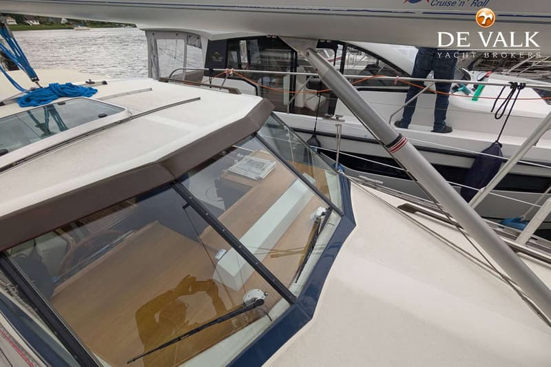 Een deel van een boot met een voorruit, ruitenwissers en een houten dashboard, met een andere boot ernaast. — LM 35 Vitesse