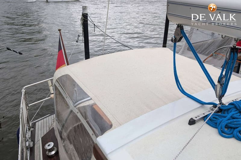 Een bovenaanzicht van een boot met een beige buiskap, blauwe touwen en een Duitse vlag. — LM 35 Vitesse