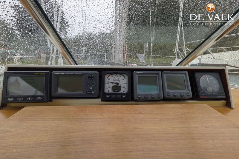 Een dashboard met zes navigatie-instrumenten, waaronder een Clipper Navtex, Furuno GPS, Simrad windmeter, twee Raymarine…