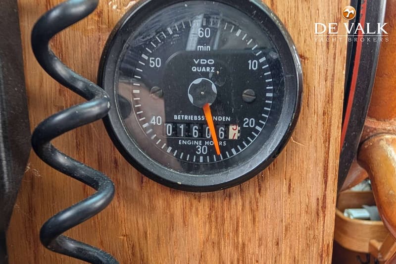 Een close-up van een zwart VDO Quartz toerenteller met een oranje wijzer en een digitale urenteller die 01606.7 aangeeft.