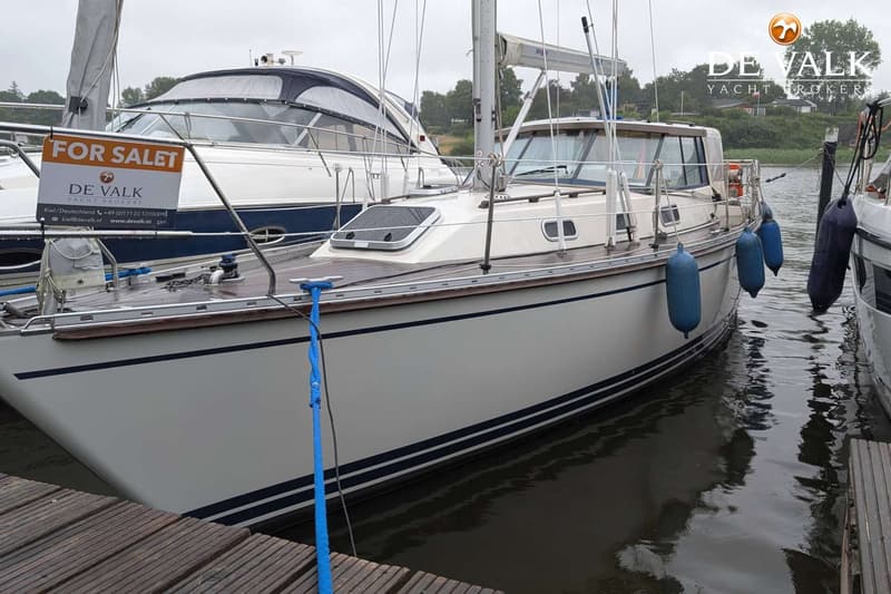 Een witte zeilboot met twee blauwe strepen op de romp ligt aangemeerd naast een houten steiger. — LM 35 Vitesse