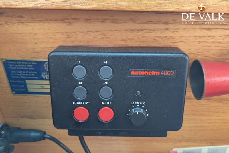 Een zwarte Autohelm 4000 stuurautomaat met knoppen en een draaiknop, gemonteerd op een houten oppervlak.