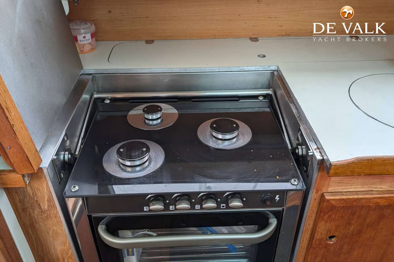 Een fornuis met drie kookpitten en een oven is ingebouwd in een houten aanrechtblad.