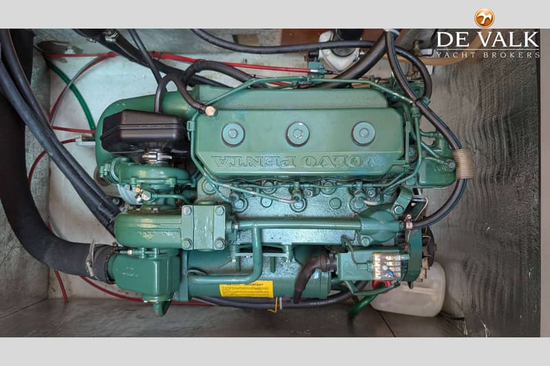 Een groene Volvo Penta scheepsmotor met diverse slangen en kabels is zichtbaar in een motorruimte.