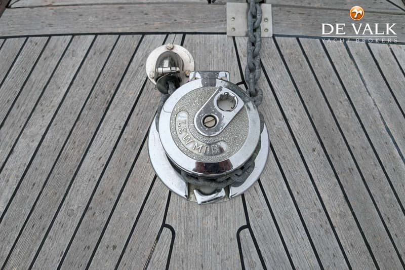 Een Lewmar lier met ketting en een kikkertje op een houten dek.