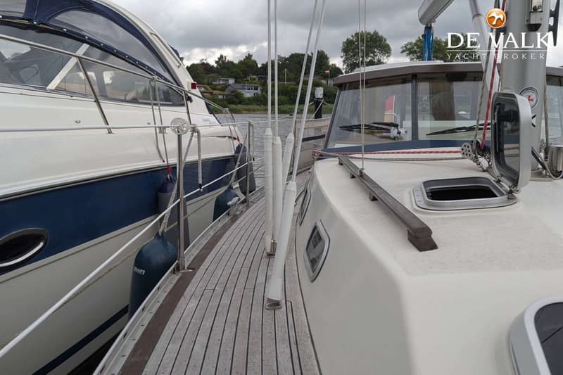 Een houten dek van een zeilboot met een open luik en een deel van een andere boot ernaast. — LM 35 Vitesse