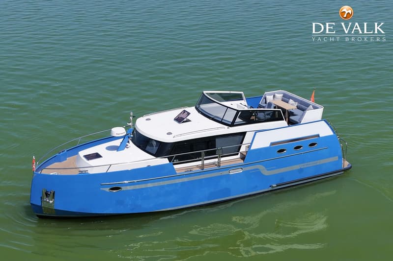 Een blauw-witte motorboot met een teakdek en een Raymarine radar op het voordek, drijft op groen water.