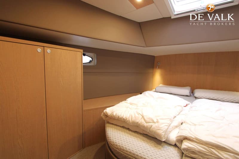 Een kajuit met een tweepersoonsbed, houten kasten, een patrijspoort en een dakluik. — Thomasz Yacht 412 AC