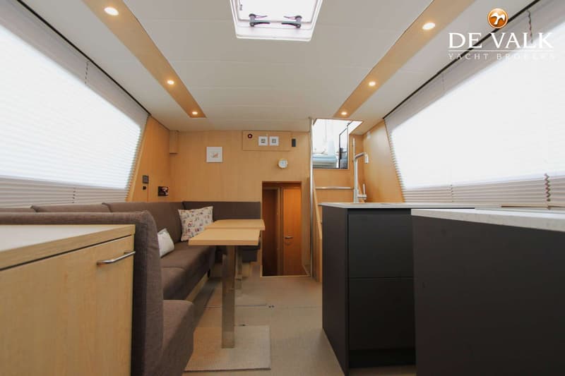 Een interieur van een boot met een zithoek, tafel, keukenblok, trap en een patrijspoort. — Thomasz Yacht 412 AC