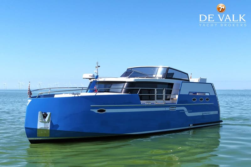 Een blauw-witte motorboot met de naam "THOMASZ" ligt op het water met windmolens op de achtergrond. — Thomasz Yacht 412 AC