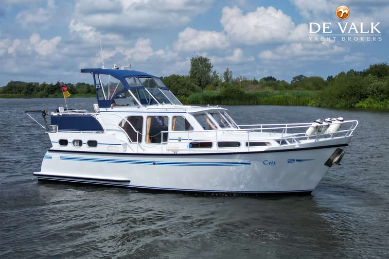Een witte motorboot met blauwe accenten en de naam "Cris" op de boeg vaart op een waterweg. — Pedro Skiron 35