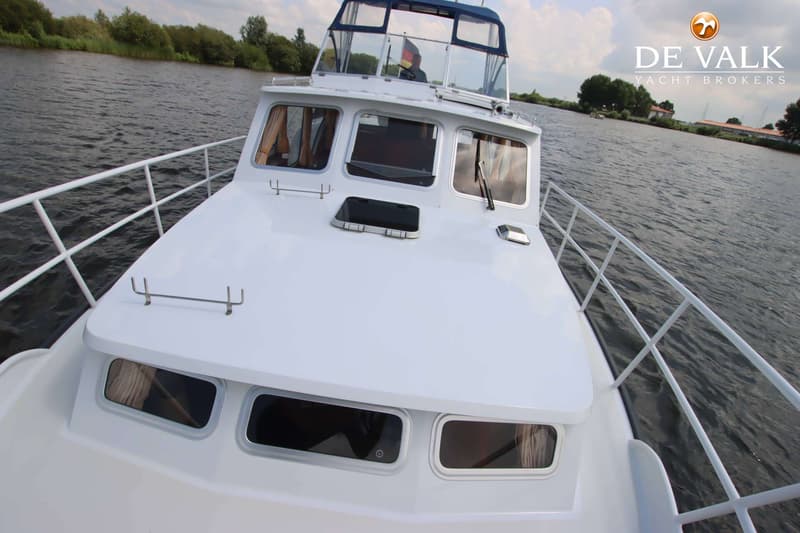 Een witte boot vaart op een waterweg met bomen langs de oever en een blauwe bimini-top. — Pedro Skiron 35