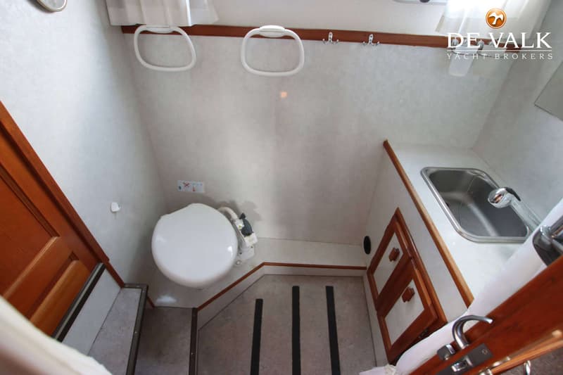 Een bootinterieur met een toilet, een wastafel en houten kasten.