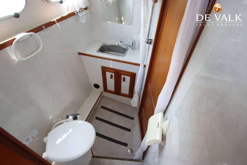De foto toont een badkamer met een toilet, wastafel, spiegel, douche en een houten kastje.