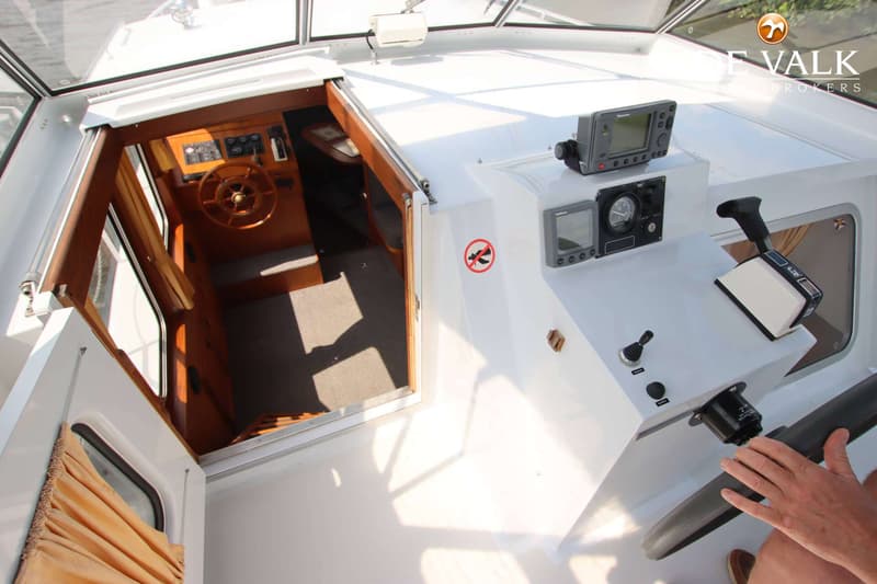 Een bovenaanzicht van de cockpit van een boot met een houten stuurwiel en navigatie-instrumenten. — Pedro Skiron 35