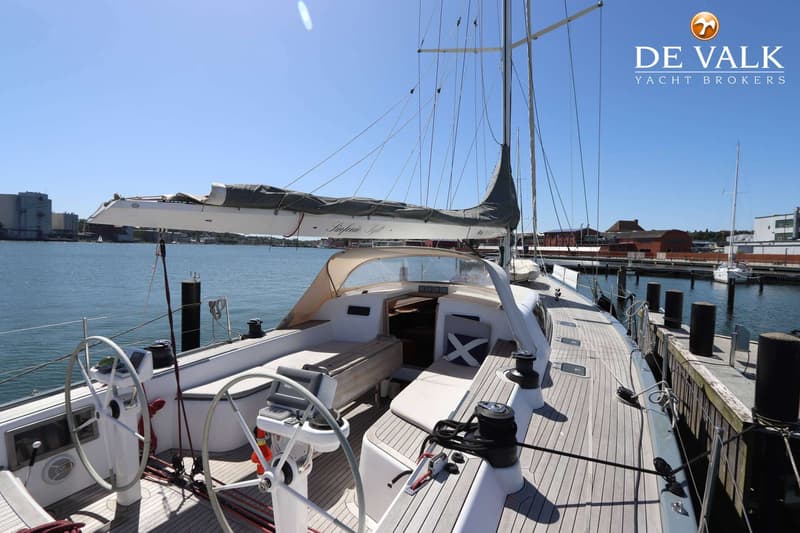 Een zeilboot met twee stuurwielen en een houten dek ligt aangemeerd aan een steiger op een zonnige dag. — Grand Soleil 70