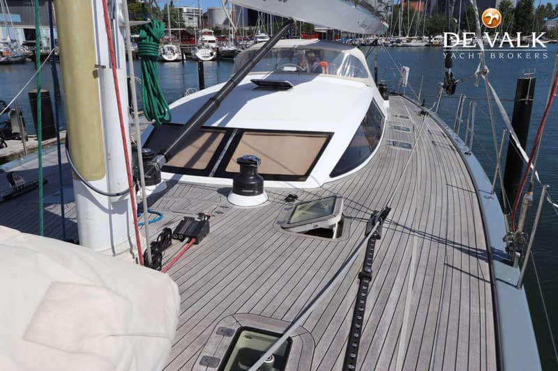 Een bovenaanzicht van het teakhouten dek van een zeilboot met een witte kajuitopbouw en een lier. — Grand Soleil 70