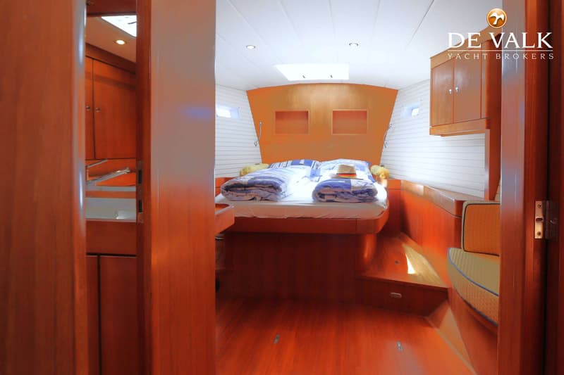 Een slaapkamer in een boot met een groot bed, houten vloer en wanden, en een wit plafond met verlichting. — Grand Soleil 70