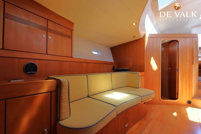 Een interieur van een boot met houten wanden, een gele bank met blauwe bies en een open deur. — Grand Soleil 70