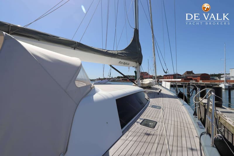 Een zeilboot met een grijze zeilhoes en een witte buiskap ligt aangemeerd aan een houten steiger. — Grand Soleil 70