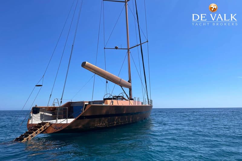 Een zeilboot met een bruine romp en een uitklapbare zwemtrap aan de achterzijde ligt in helderblauw water. — Wally 88