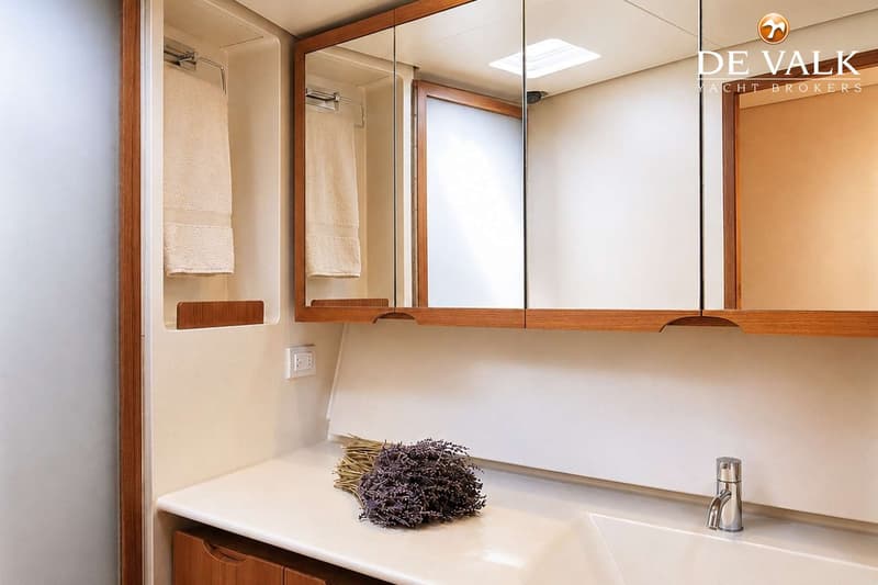 Een badkamer met een wastafel, een kraan, een bos lavendel, een spiegelkast en handdoeken.
