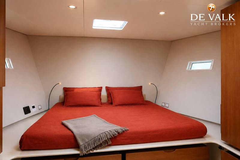 Een kajuit met een tweepersoonsbed met rood beddengoed, twee kussens en een grijze plaid. — Wally 88