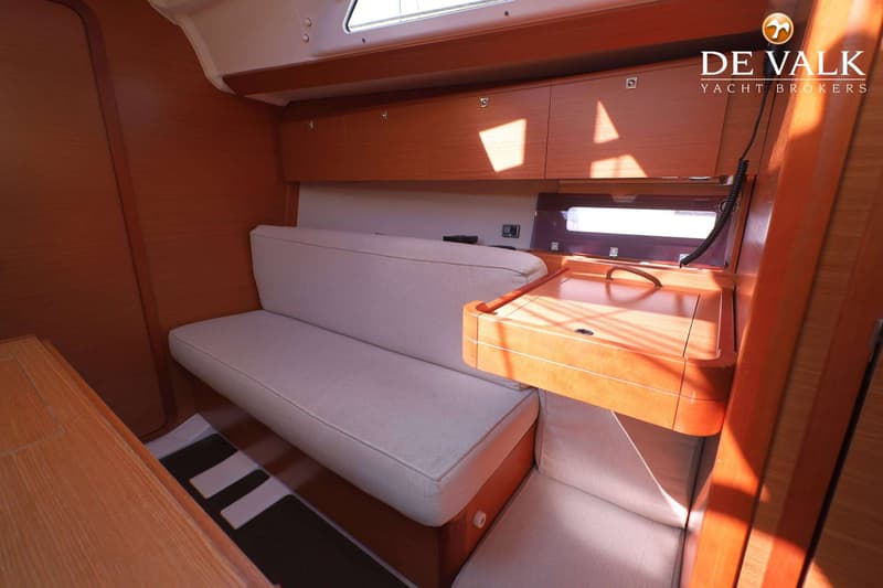 De foto toont een interieur van een boot met houten wanden, een lichte bank en een houten tafel. — Dufour 360 GL