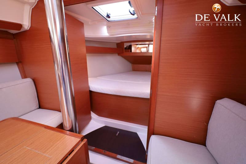 De foto toont een interieur van een boot met een bed, een tafel, zitbanken en een luik in het plafond. — Dufour 360 GL