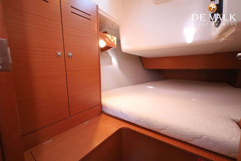 Een kajuit met een bed, houten kasten en een lampje, met het logo van "De Valk Yacht Brokers" rechtsboven. — Dufour 360 GL