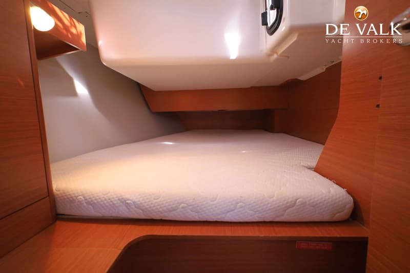 Een kajuit met een wit matras, houten wanden en een lampje aan de linkerkant. — Dufour 360 GL
