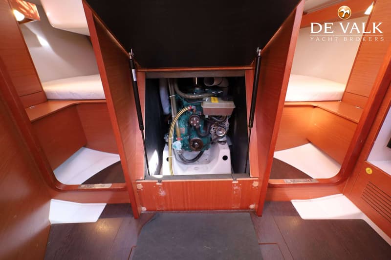 Een open motorruimte met een motor en twee bedden met witte matrassen aan weerszijden.