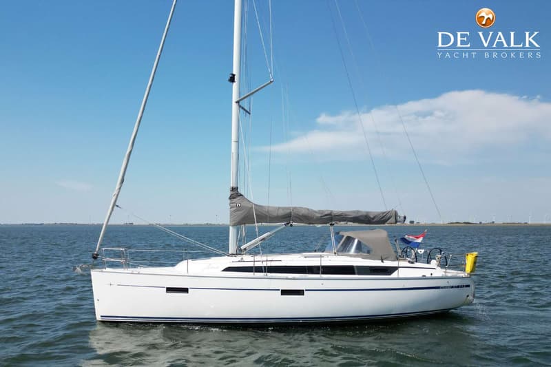 Een witte zeilboot met een blauwe streep op de romp vaart op rustig water onder een helderblauwe lucht. — Bavaria 37 Cruiser