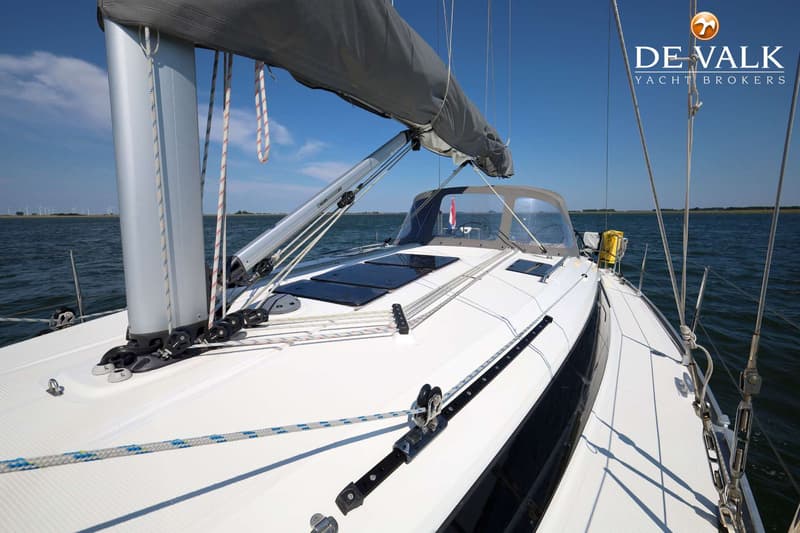 Een witte zeilboot met een grijs zeil en een blauwe romp vaart op helder water onder een blauwe lucht. — Bavaria 37 Cruiser