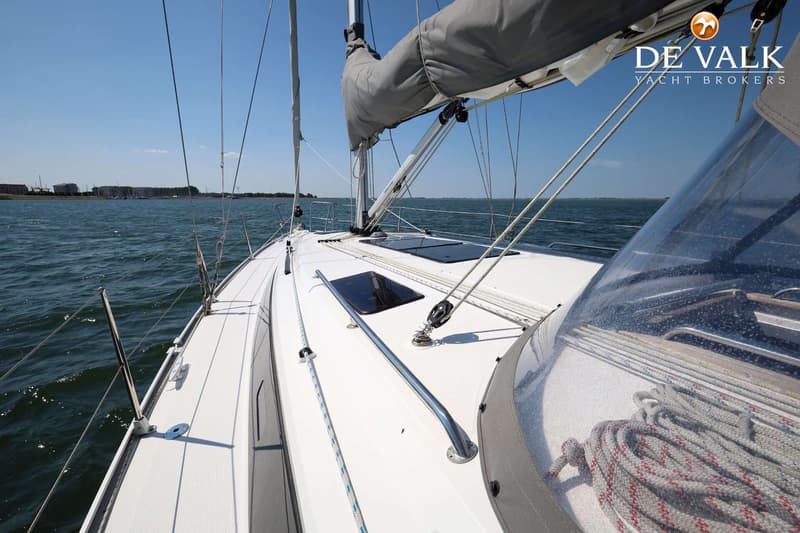 Een witte zeilboot vaart op open water met een opgerold zeil en een helderblauwe lucht. — Bavaria 37 Cruiser