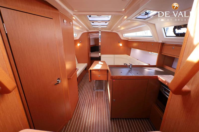 De foto toont het interieur van een boot met een houten vloer, een kombuis, een tafel en zitbanken. — Bavaria 37 Cruiser