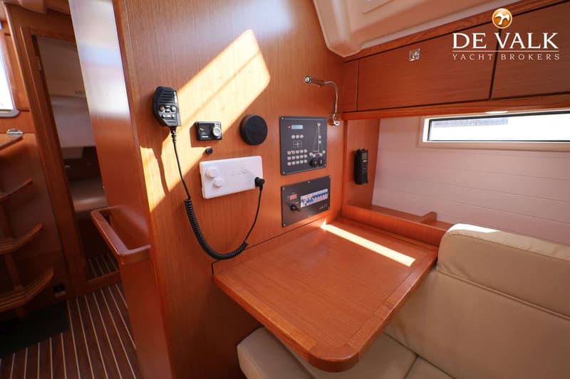 Een houten interieur van een boot met een bedieningspaneel, een marifoon en een tafel. — Bavaria 37 Cruiser