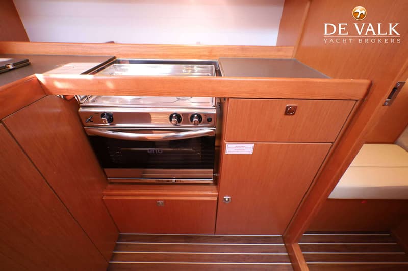 Een roestvrijstalen fornuis met oven is ingebouwd in een houten keukenblok met kasten en een aanrecht.