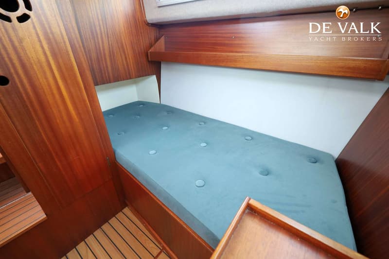 Een kajuit met een blauw gestoffeerd bed, houten wanden en een houten vloer. — Storebro Royal Cruiser 31 Baltic