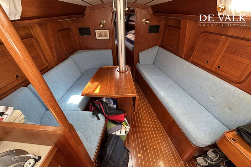 De foto toont het interieur van een boot met houten wanden en vloer, lichtblauwe banken en een houten tafel. — Maestro 35