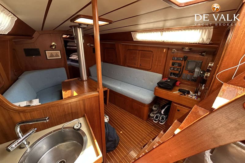 De foto toont het interieur van een boot met houten afwerking, zitbanken, een kombuis en navigatieapparatuur. — Maestro 35
