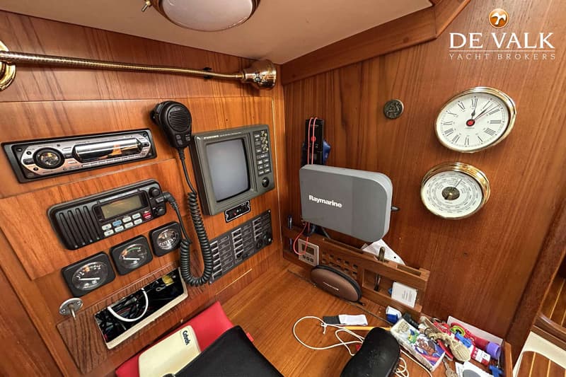 Een houten interieur met diverse navigatie-instrumenten, meters, een radio en een klok met barometer.