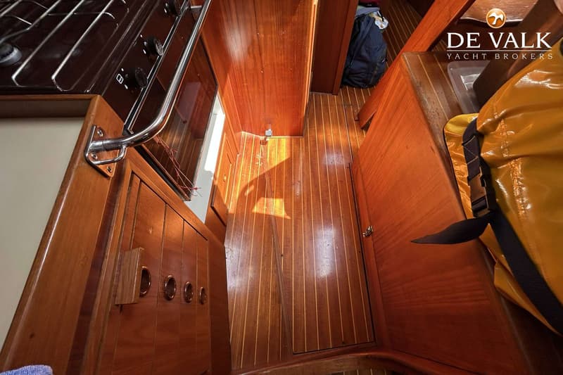 Een interieur van een boot met houten vloer en wanden, een fornuis en een gele tas. — Maestro 35