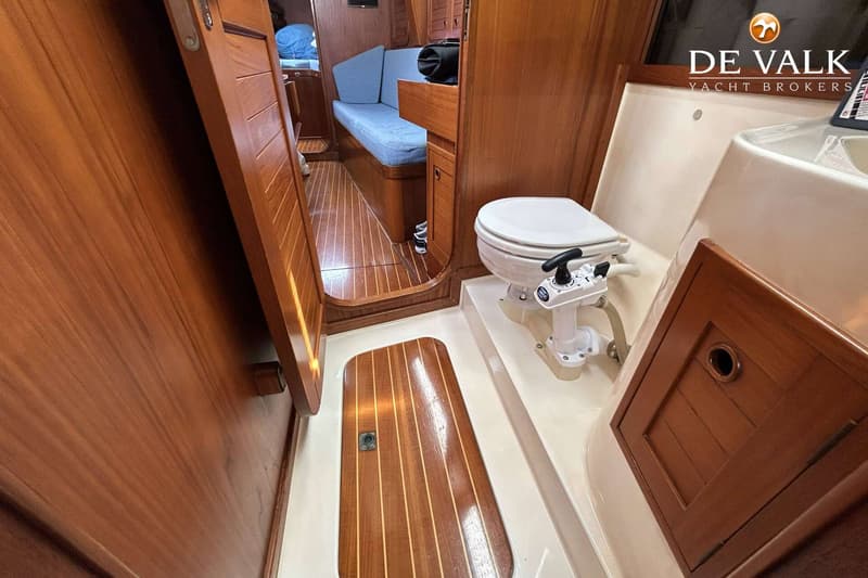 De foto toont een interieur van een boot met een toilet, houten vloer en houten wanden, en een blauwe bank. — Maestro 35