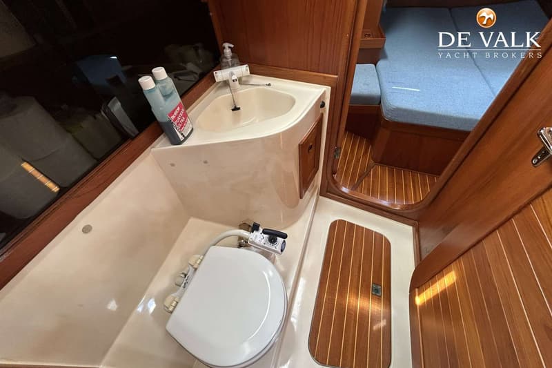 De foto toont een toiletruimte met een wastafel, een toilet en een houten vloer in een boot. — Maestro 35