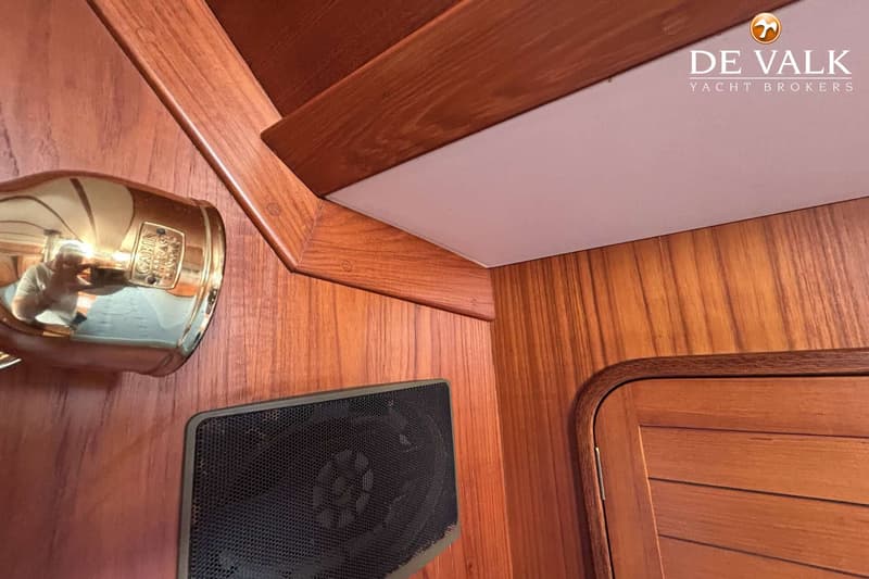 Een interieur met houten wanden, een gouden klok met "CABIN" erop, een zwarte luidspreker en een houten deur.