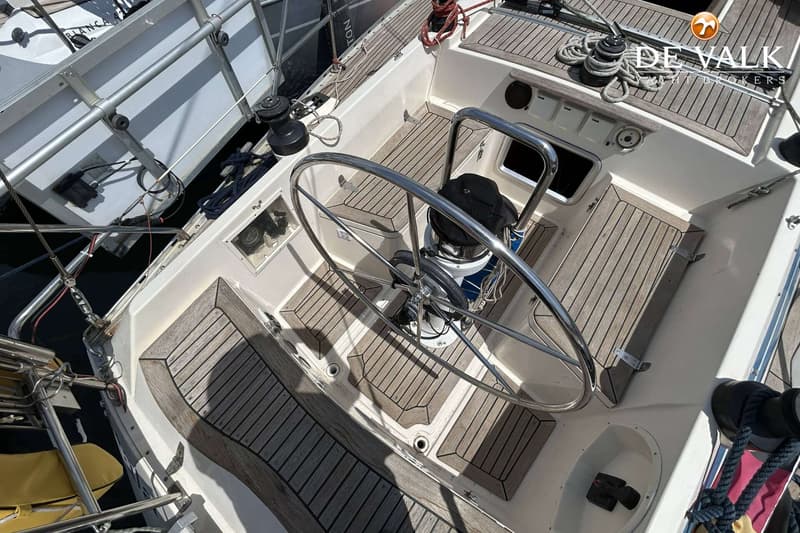 Een bovenaanzicht van de kuip van een zeilboot met een groot stuurwiel, teakhouten dek en een kompas. — Maestro 35